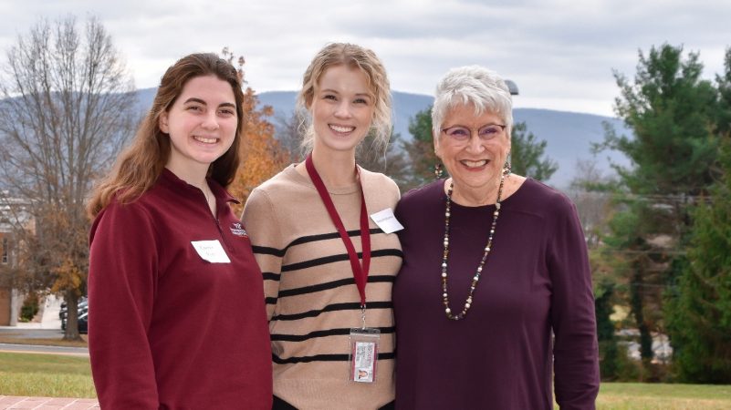 Marty Holliday, Makenzie Mann, and Ashley Posthumus posing for a picture in front of a mountain landscape