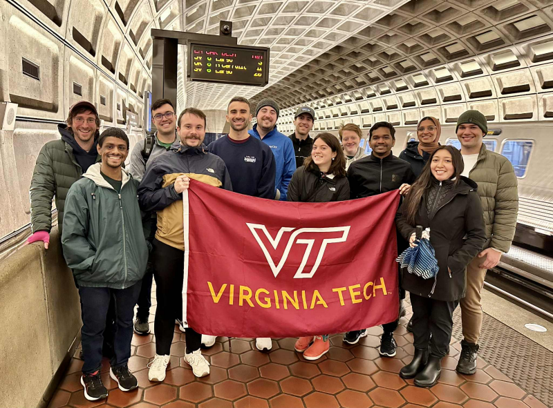 A diverse group of MURP at Virginia Tech Students in the DC metro subway holding a Virginia Tech flag